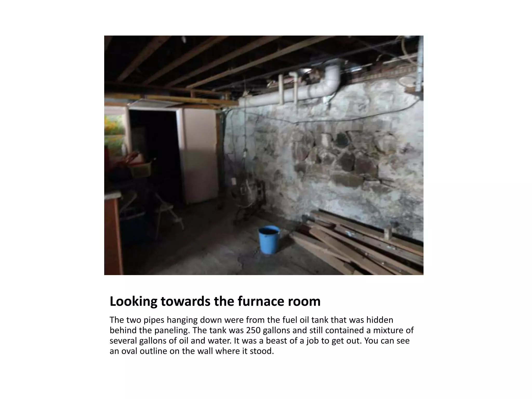 Looking towards the furnace room
The two pipes hanging down were from the fuel oil tank that was hidden
behind the paneling. The tank was 250 gallons and still contained a mixture of
several gallons of oil and water. It was a beast of a job to get out. You can see
an oval outline on the wall where it stood.
 