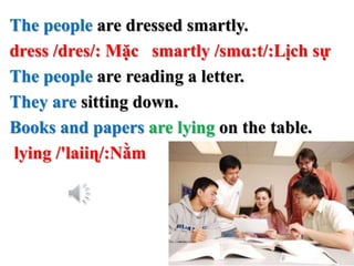 The people are dressed smartly.
dress /dres/: Mặc smartly /smɑ:t/:Lịch sự
The people are reading a letter.
They are sitting down.
Books and papers are lying on the table.
lying /'laiiɳ/:Nằm
 