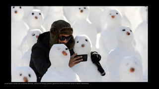 A man takes a photo with snowmen Saturday, January 24, during a protest against the World Economic Forum in Davos, Switzer...