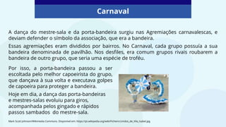Carnaval
Mark Scott Johnson/Wikimedia Commons. Disponível em: https://pt.wikipedia.org/wiki/Ficheiro:Unidos_de_Vila_Isabel.jpg
A dança do mestre-sala e da porta-bandeira surgiu nas Agremiações carnavalescas, e
deviam defender o símbolo da associação, que era a bandeira.
Essas agremiações eram divididos por bairros. No Carnaval, cada grupo possuía a sua
bandeira denominada de pavilhão. Nos desfiles, era comum grupos rivais roubarem a
bandeira de outro grupo, que seria uma espécie de troféu.
Por isso, a porta-bandeira passou a ser
escoltada pelo melhor capoeirista do grupo,
que dançava à sua volta e executava golpes
de capoeira para proteger a bandeira.
Hoje em dia, a dança das porta-bandeiras
e mestres-salas evoluiu para giros,
acompanhada pelos gingado e rápidos
passos sambados do mestre-sala.
 