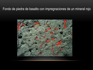 Fondo de piedra de basalto con impregnaciones de un mineral rojo
 