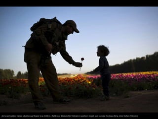 An Israeli soldier hands a buttercup flower to a child in a field near Kibbutz Nir Yitzhak in southern Israel, just outsid...