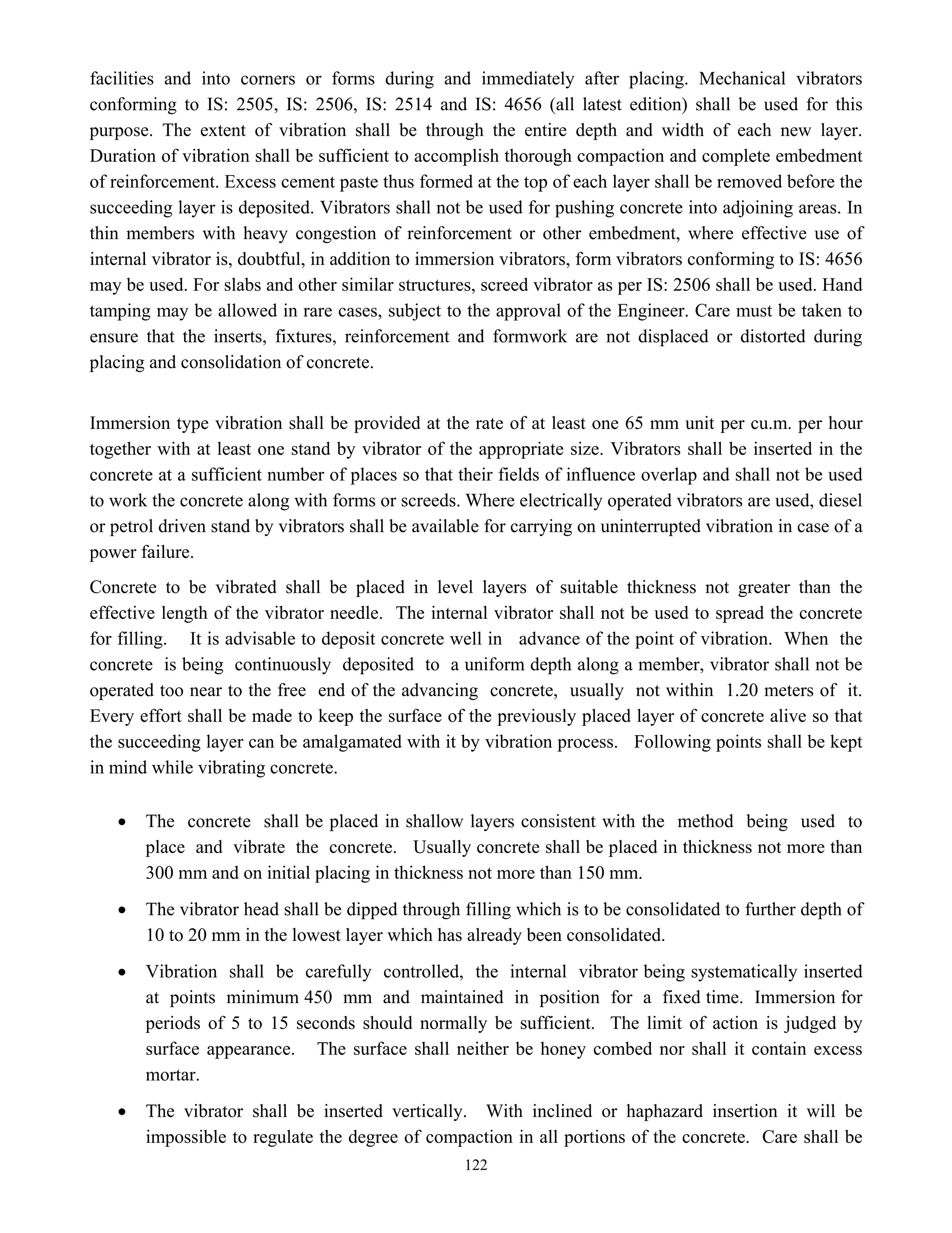 122
facilities and into corners or forms during and immediately after placing. Mechanical vibrators
conforming to IS: 2505, IS: 2506, IS: 2514 and IS: 4656 (all latest edition) shall be used for this
purpose. The extent of vibration shall be through the entire depth and width of each new layer.
Duration of vibration shall be sufficient to accomplish thorough compaction and complete embedment
of reinforcement. Excess cement paste thus formed at the top of each layer shall be removed before the
succeeding layer is deposited. Vibrators shall not be used for pushing concrete into adjoining areas. In
thin members with heavy congestion of reinforcement or other embedment, where effective use of
internal vibrator is, doubtful, in addition to immersion vibrators, form vibrators conforming to IS: 4656
may be used. For slabs and other similar structures, screed vibrator as per IS: 2506 shall be used. Hand
tamping may be allowed in rare cases, subject to the approval of the Engineer. Care must be taken to
ensure that the inserts, fixtures, reinforcement and formwork are not displaced or distorted during
placing and consolidation of concrete.
Immersion type vibration shall be provided at the rate of at least one 65 mm unit per cu.m. per hour
together with at least one stand by vibrator of the appropriate size. Vibrators shall be inserted in the
concrete at a sufficient number of places so that their fields of influence overlap and shall not be used
to work the concrete along with forms or screeds. Where electrically operated vibrators are used, diesel
or petrol driven stand by vibrators shall be available for carrying on uninterrupted vibration in case of a
power failure.
Concrete to be vibrated shall be placed in level layers of suitable thickness not greater than the
effective length of the vibrator needle. The internal vibrator shall not be used to spread the concrete
for filling. It is advisable to deposit concrete well in advance of the point of vibration. When the
concrete is being continuously deposited to a uniform depth along a member, vibrator shall not be
operated too near to the free end of the advancing concrete, usually not within 1.20 meters of it.
Every effort shall be made to keep the surface of the previously placed layer of concrete alive so that
the succeeding layer can be amalgamated with it by vibration process. Following points shall be kept
in mind while vibrating concrete.
• The concrete shall be placed in shallow layers consistent with the method being used to
place and vibrate the concrete. Usually concrete shall be placed in thickness not more than
300 mm and on initial placing in thickness not more than 150 mm.
• The vibrator head shall be dipped through filling which is to be consolidated to further depth of
10 to 20 mm in the lowest layer which has already been consolidated.
• Vibration shall be carefully controlled, the internal vibrator being systematically inserted
at points minimum 450 mm and maintained in position for a fixed time. Immersion for
periods of 5 to 15 seconds should normally be sufficient. The limit of action is judged by
surface appearance. The surface shall neither be honey combed nor shall it contain excess
mortar.
• The vibrator shall be inserted vertically. With inclined or haphazard insertion it will be
impossible to regulate the degree of compaction in all portions of the concrete. Care shall be
 