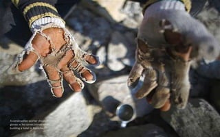 A construction worker shows his torn
gloves as he carves stones while
building a hotel in Namche.
 