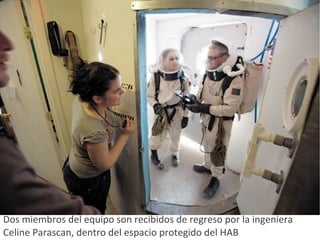 Dos miembros del equipo son recibidos de regreso por la ingeniera Celine Parascan, dentro del espacio protegido del HAB  
