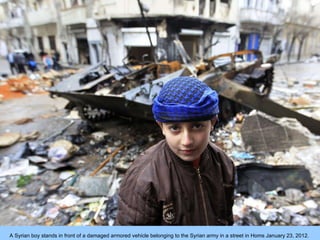 A Syrian boy stands in front of a damaged armored vehicle belonging to the Syrian army in a street in Homs January 23, 201...