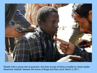 Rebels hold a young man at gunpoint, who they accuse of being a loyalist to Libyan leader Muammar Gaddafi, between the towns of Brega and Ras Lanuf, March 3, 2011.  