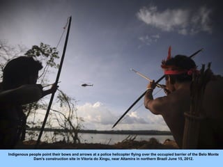 Indigenous people point their bows and arrows at a police helicopter flying over the occupied barrier of the Belo Monte
  ...