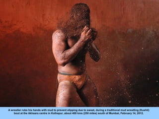 A wrestler rubs his hands with mud to prevent slipping due to sweat, during a traditional mud wrestling (Kushti)
    bout ...