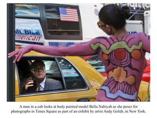 A man in a cab looks at body painted model Bella Nabiyah as she poses for
photographs in Times Square as part of an exhibit by artist Andy Golub, in New York.
 