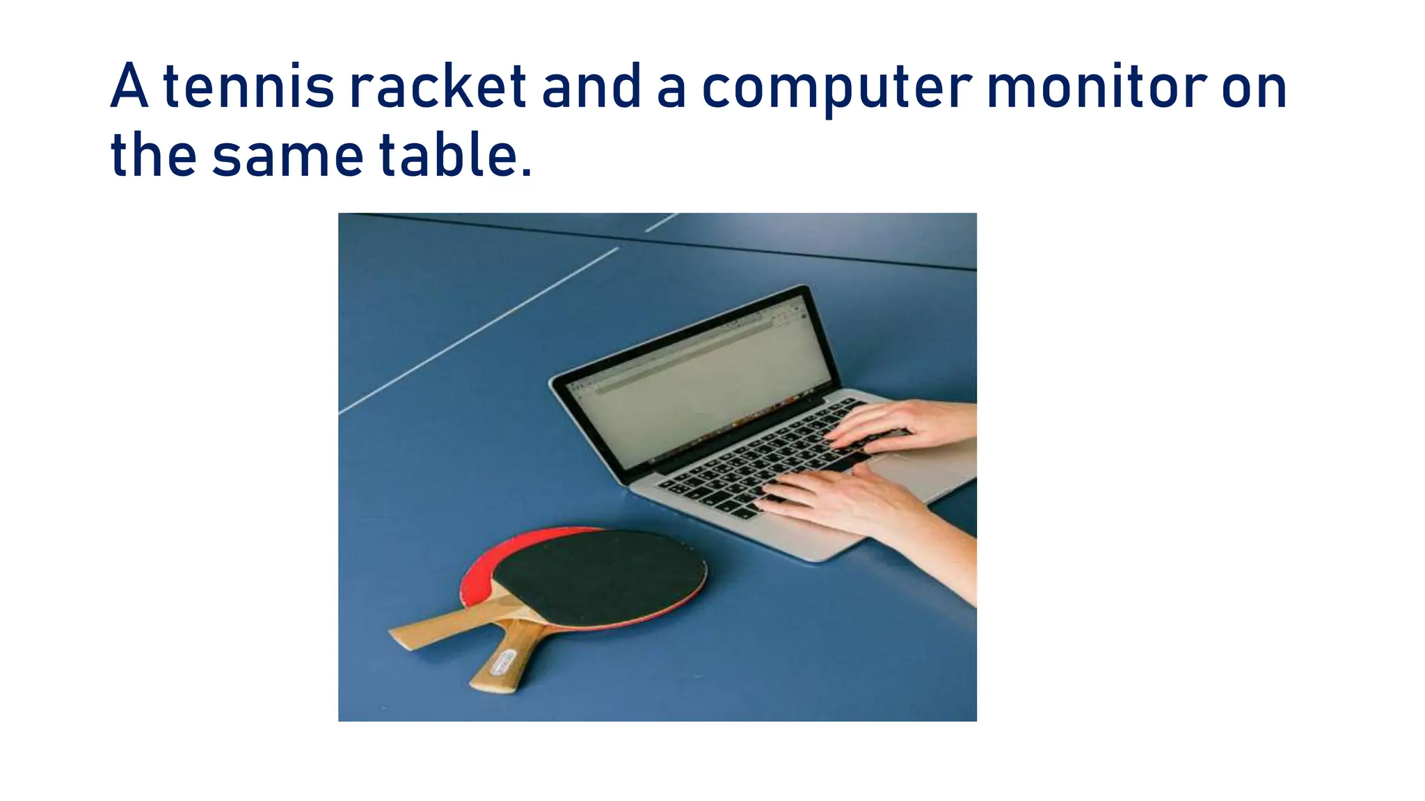 A tennis racket and a computer monitor on
the same table.