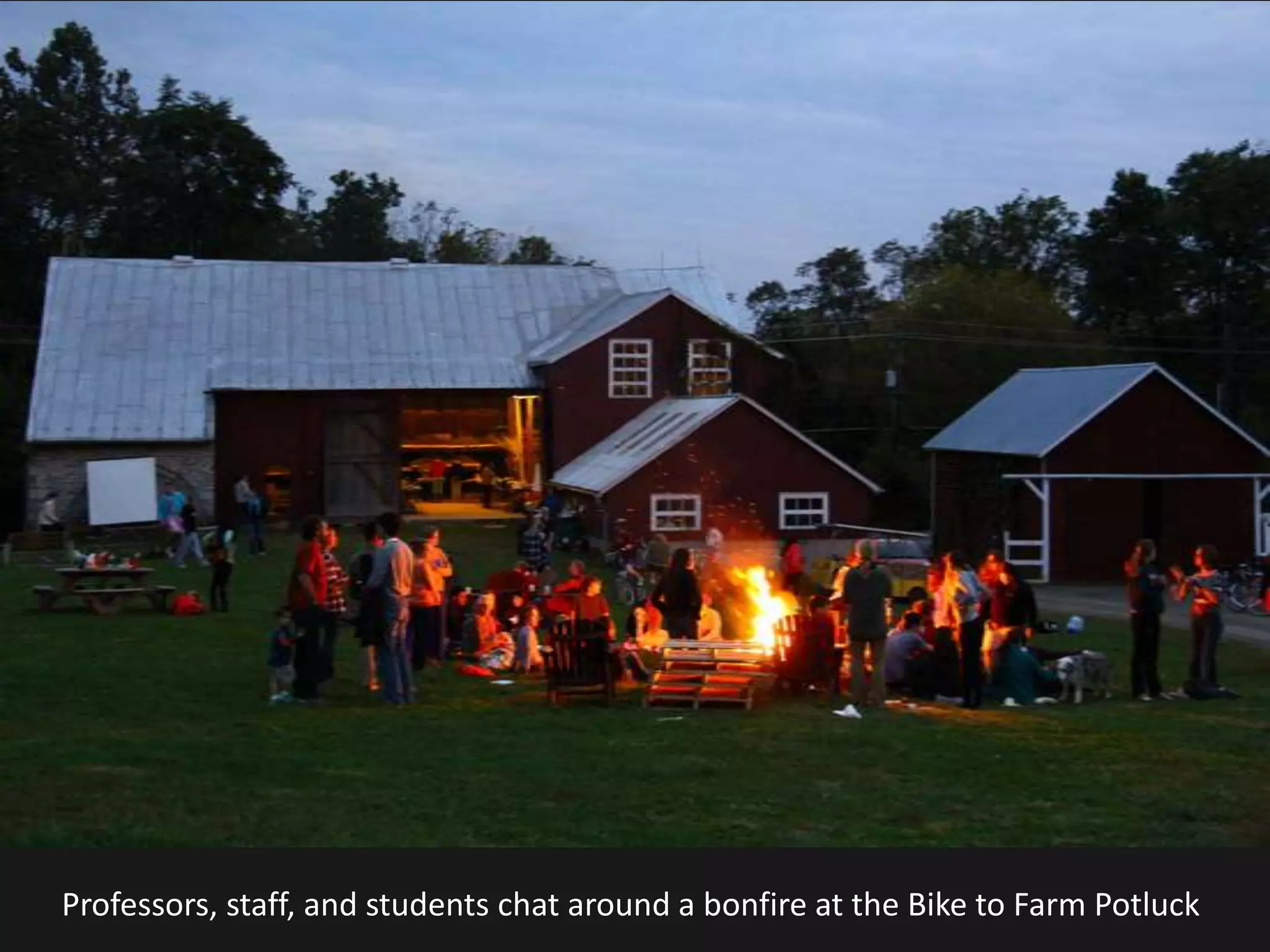 Professors, staff, and students chat around a bonfire at the Bike to Farm Potluck
 