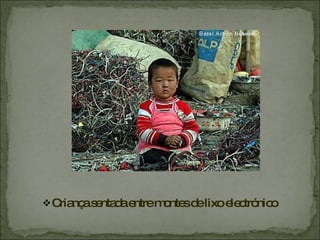 Criança sentada entre montes de lixo electrónico 