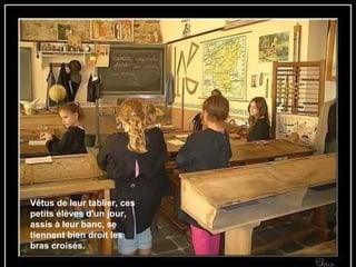 Vêtus de leur tablier, ces petits élèves d'un jour, assis à leur banc, se tiennent bien droit les bras croisés. 