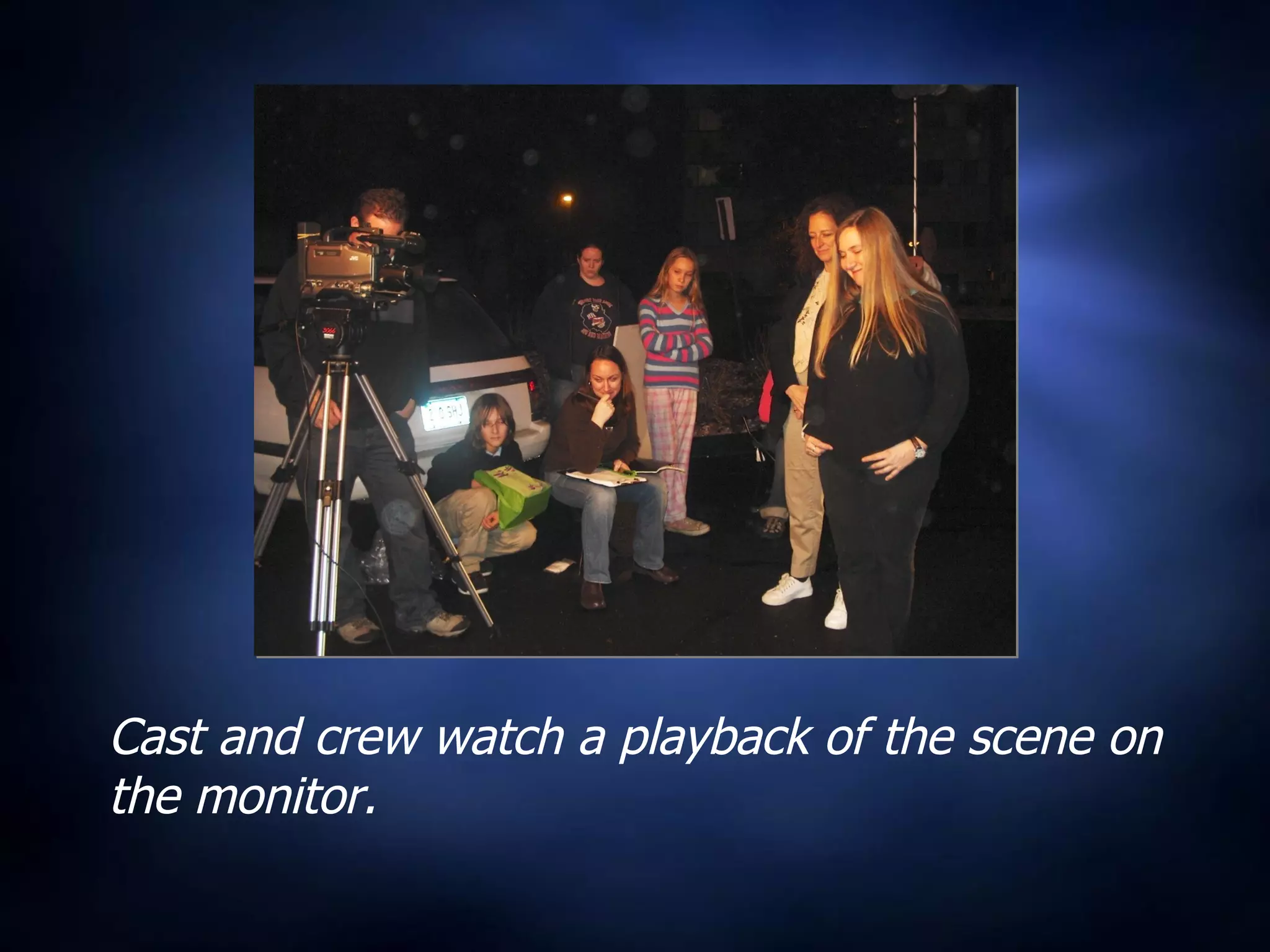 Cast and crew watch a playback of the scene on the monitor. 