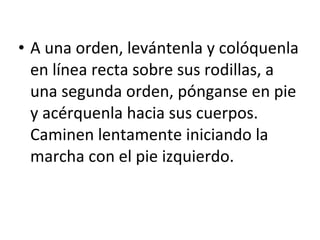 A una orden, levántenla y colóquenla en línea recta sobre sus rodillas, a una segunda orden, pónganse en pie y acérquenla hacia sus cuerpos. Caminen lentamente iniciando la marcha con el pie izquierdo. 