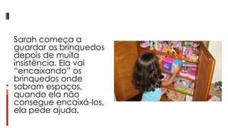 Sarah começa a guardar os brinquedos depois de muita insistência. Ela vai “encaixando” os brinquedos onde sobram espaços, quando ela não consegue encaixá-los, ela pede ajuda.  