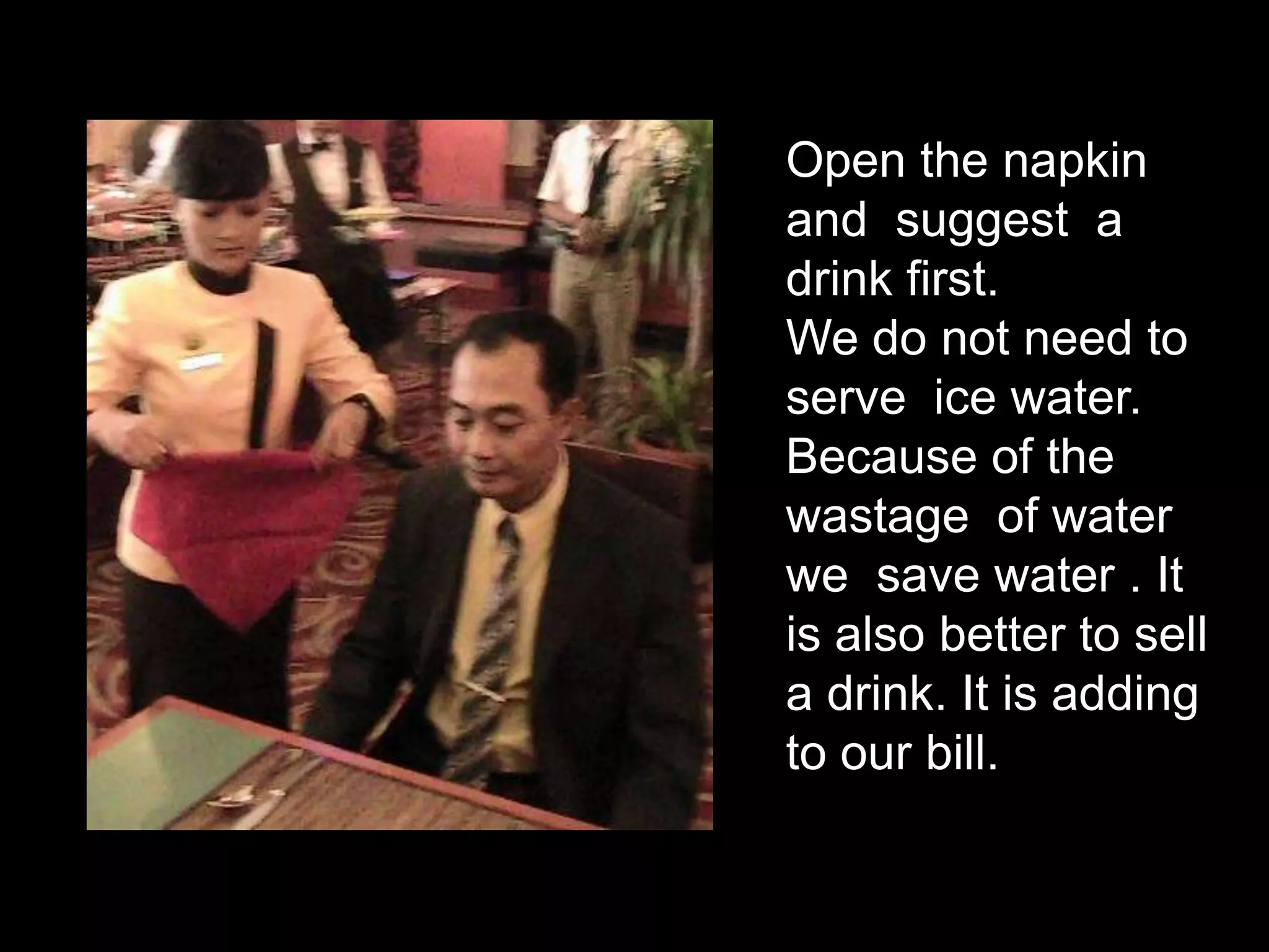 Open the napkin and  suggest  a  drink first. We do not need to serve  ice water. Because of the wastage  of water  we  save water . It is also better to sell a drink. It is adding to our bill.