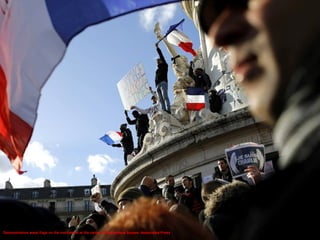 Demonstrators wave flags on the monument at the center of Republique Square. Associated Press
 