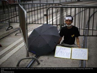 A man holds a sign which read 'For democracy with peace' as protesters block a street near the government headquarters building in Hong Kong, September 30, 
2014. 
REUTERS/Carlos Barria 
 