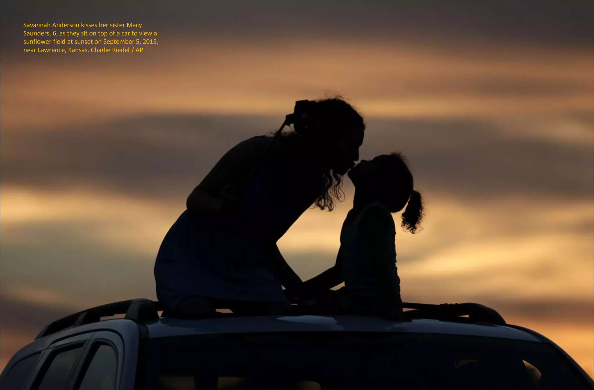 Savannah Anderson kisses her sister Macy
Saunders, 6, as they sit on top of a car to view a
sunflower field at sunset on September 5, 2015,
near Lawrence, Kansas. Charlie Riedel / AP
 