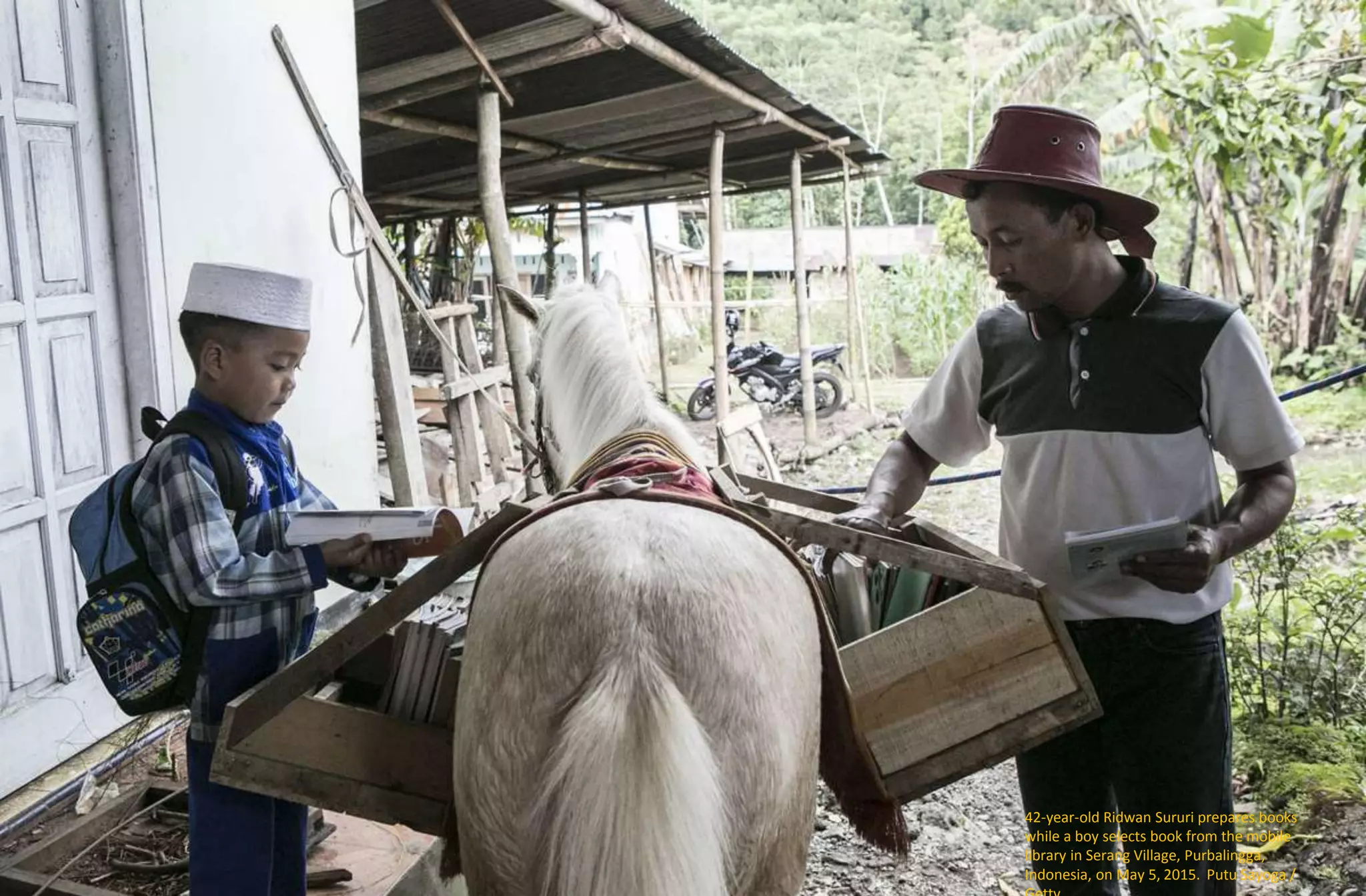 42-year-old Ridwan Sururi prepares books
while a boy selects book from the mobile
library in Serang Village, Purbalingga,
Indonesia, on May 5, 2015. Putu Sayoga /
 