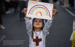 Maria Sole, age 4, dressed in a nurse's outfit, holds up a rainbow
drawing with the words 'Thank You' on it as NHS staff a...