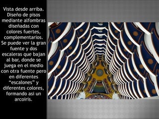 Vista desde arriba. Diseño de pisos mediante alfombras diseñadas con colores fuertes, complementarios. Se puede ver la gran fuente y dos escaleras que bajan al bar, donde se juega en el medio con otra fuente pero en diferentes “escalones” y diferentes colores, formando asi un arcoiris. 