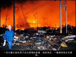 一名头戴头盔的男子走过倒塌的废墟，他的身后，一幢建筑物正在燃烧。  