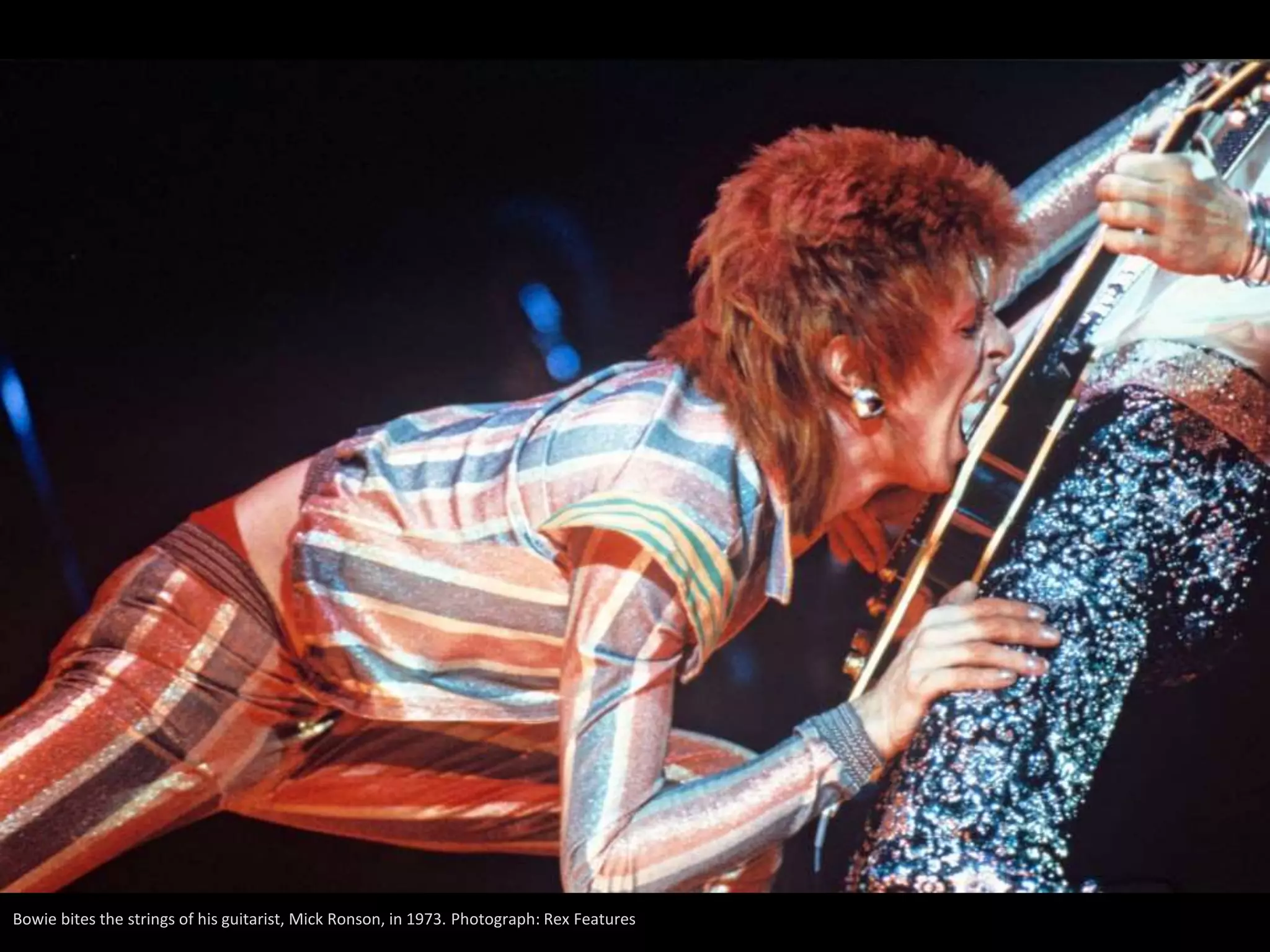 Bowie bites the strings of his guitarist, Mick Ronson, in 1973. Photograph: Rex Features
 