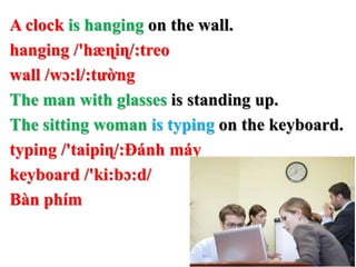 A clock is hanging on the wall.
hanging /'hæɳiɳ/:treo
wall /wɔ:l/:tường
The man with glasses is standing up.
The sitting woman is typing on the keyboard.
typing /'taipiɳ/:Đánh máy
keyboard /'ki:bɔ:d/
Bàn phím
 