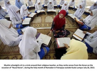 Muslim schoolgirls sit in a circle around their religious teacher, as they recite verses from the Koran on the
occasion of...