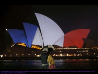 A couple stands in the rain as the blue, white and red colours of France's national flag are projected onto the sails of Sydney's Opera House in Australia November 14, 2015
following the attacks in Paris. REUTERS/Jason
 