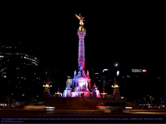 A man carries a candle and a placard with an image of the Eiffel tower in tribute to the victims of the Paris attacks in t...