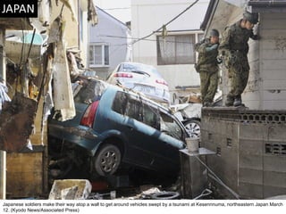 Japanese soldiers make their way atop a wall to get around vehicles swept by a tsunami at Kesennnuma, northeastern Japan March 12. (Kyodo News/Associated Press)  