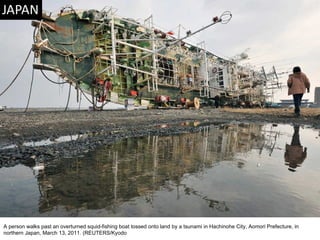 A person walks past an overturned squid-fishing boat tossed onto land by a tsunami in Hachinohe City, Aomori Prefecture, in northern Japan, March 13, 2011. (REUTERS/Kyodo  