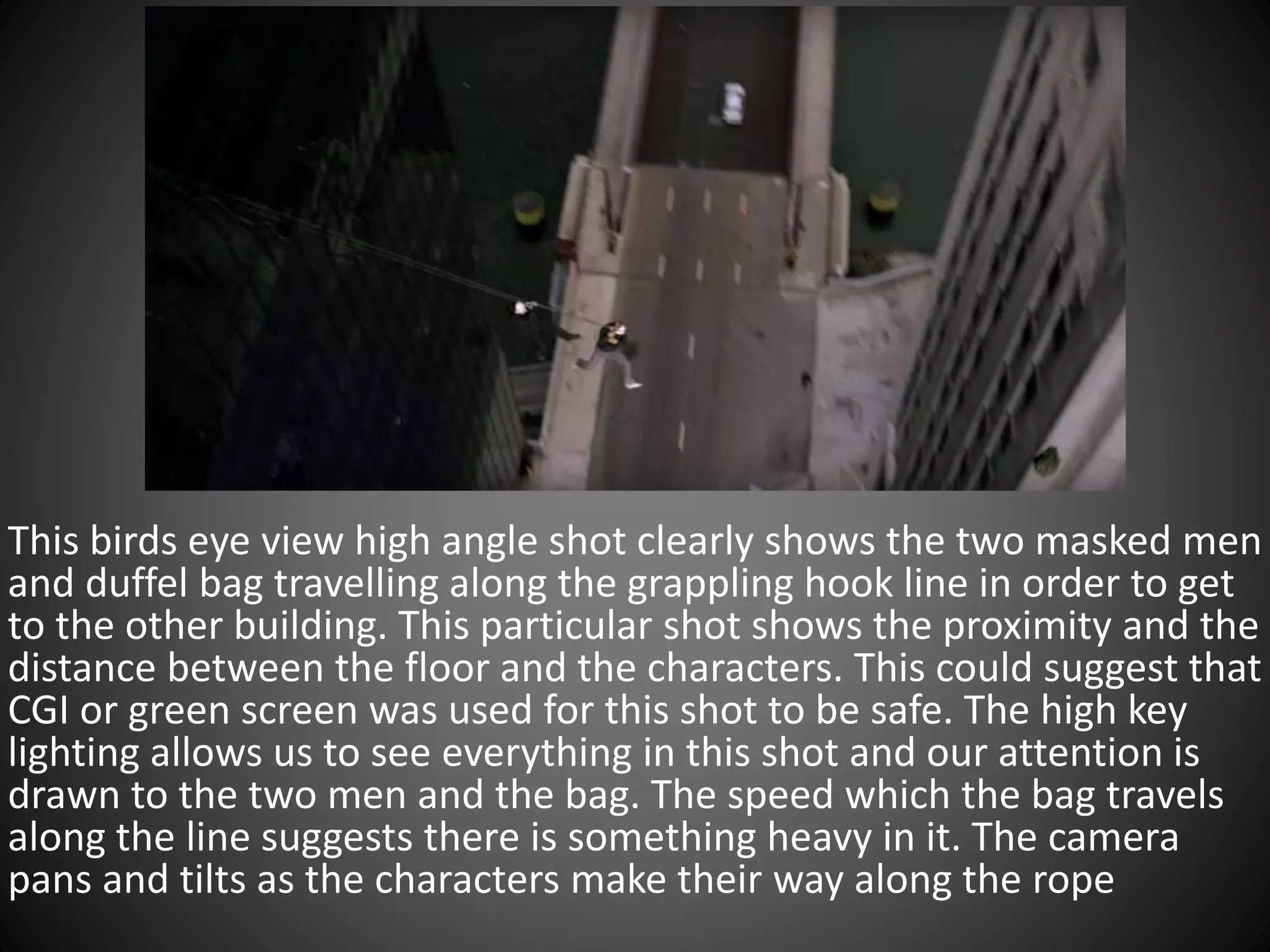 This birds eye view high angle shot clearly shows the two masked men
and duffel bag travelling along the grappling hook line in order to get
to the other building. This particular shot shows the proximity and the
distance between the floor and the characters. This could suggest that
CGI or green screen was used for this shot to be safe. The high key
lighting allows us to see everything in this shot and our attention is
drawn to the two men and the bag. The speed which the bag travels
along the line suggests there is something heavy in it. The camera
pans and tilts as the characters make their way along the rope
 