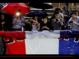 People take pictures of a makeshift memorial for the victims of the Paris attacks in front of the a French flag in Sydney, Australia, November 14, 2015. REUTERS/Jason Reed
 