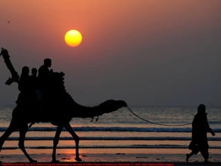 Pakistanis tourists ride on a camel during the last sunset of the year at Clifton beach in Karachi on December 31, 2014. (Asif Hassan/Getty Images)
 
