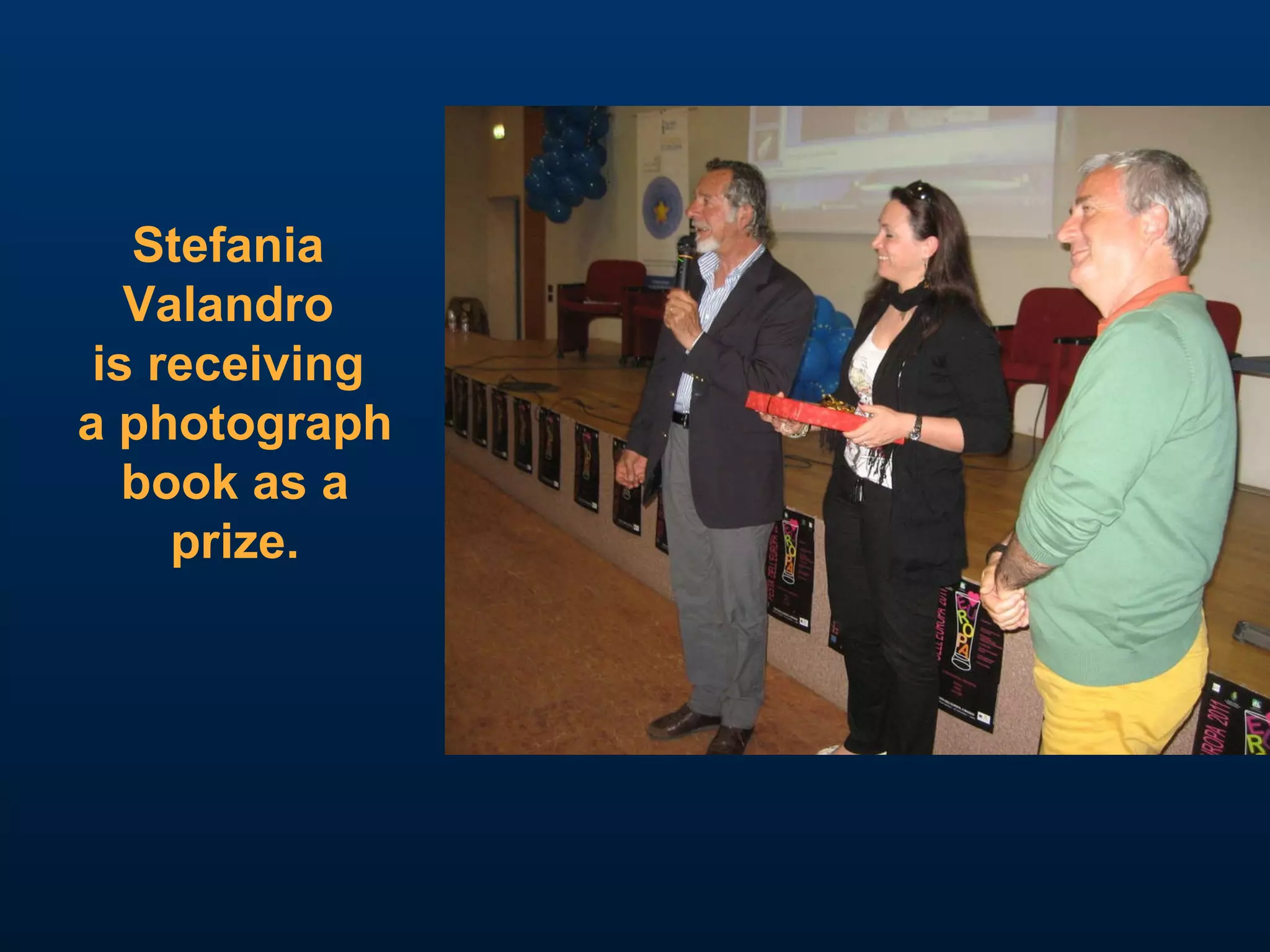 Stefania  Valandro  is receiving  a photograph book as a  prize. 