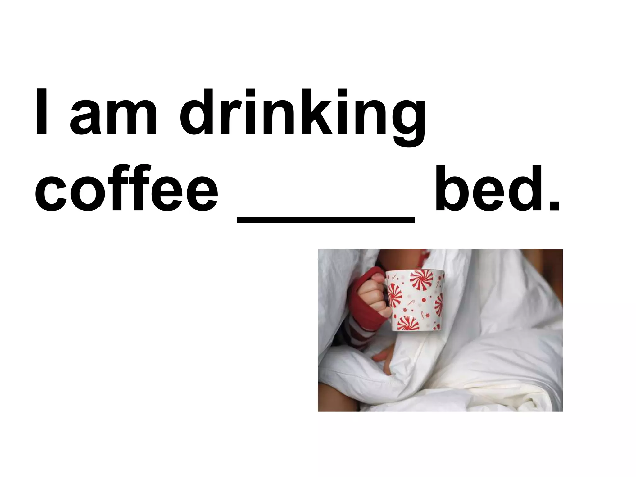 I am drinking coffee _____ bed.