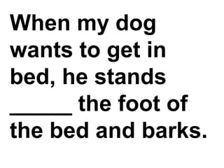 When my dog wants to get in bed, he stands _____ the foot of the bed and barks.