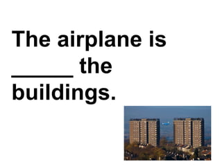 The airplane is _____ the buildings.