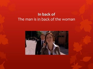 In back of 
The man is in back of the woman 
 