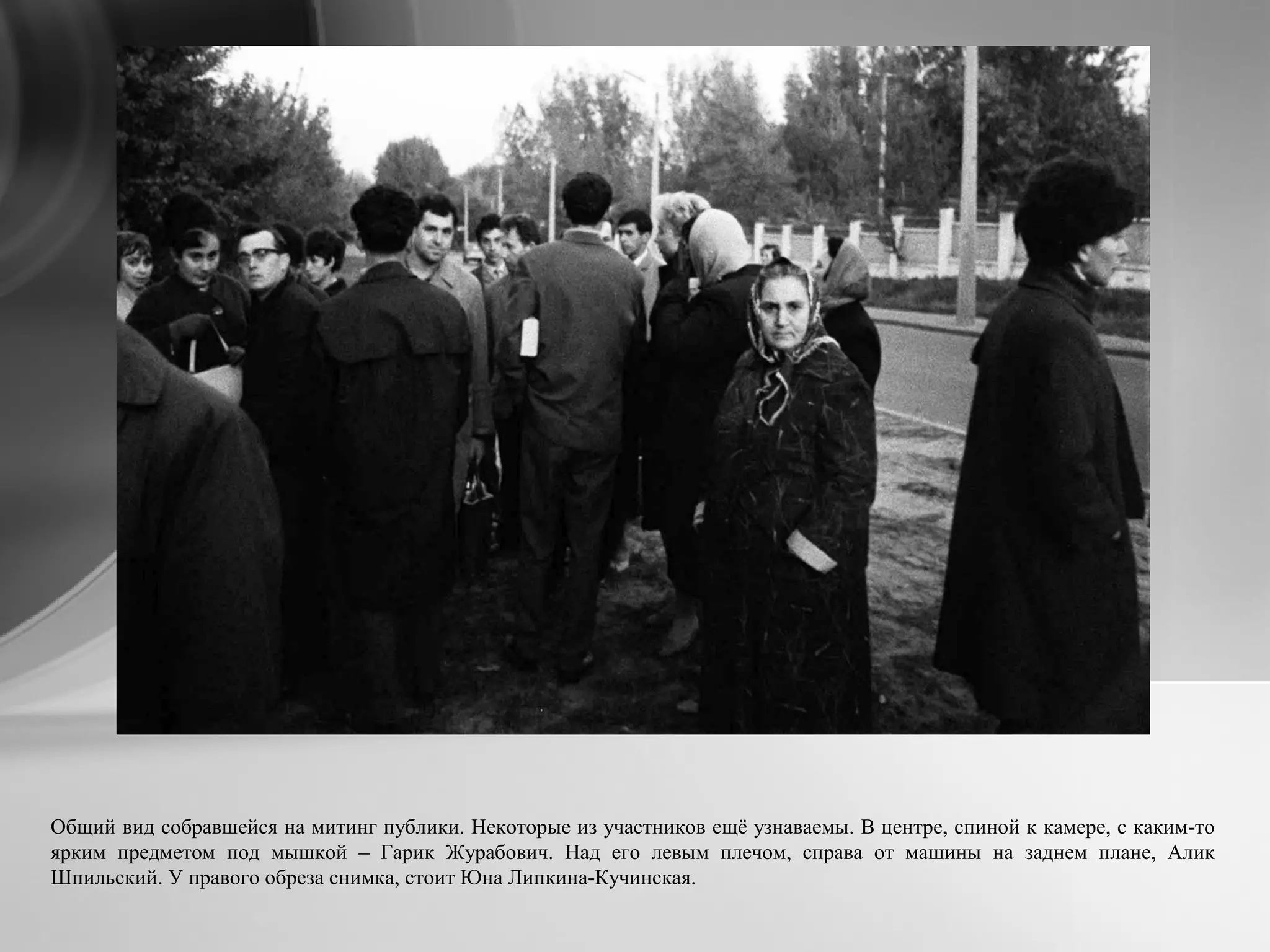 Общий вид собравшейся на митинг публики. Некоторые из участников ещё узнаваемы. В центре, спиной к камере, с каким-то
ярким предметом под мышкой – Гарик Журабович. Над его левым плечом, справа от машины на заднем плане, Алик
Шпильский. У правого обреза снимка, стоит Юна Липкина-Кучинская.
 