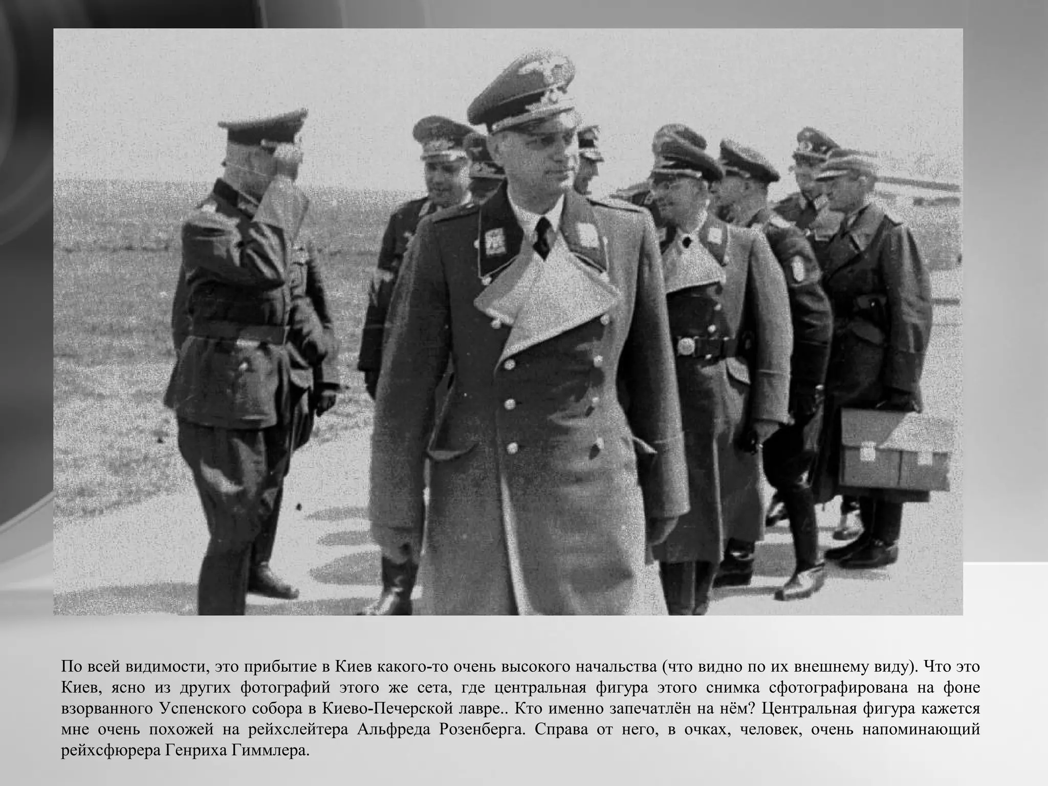 По всей видимости, это прибытие в Киев какого-то очень высокого начальства (что видно по их внешнему виду). Что это
Киев, ясно из других фотографий этого же сета, где центральная фигура этого снимка сфотографирована на фоне
взорванного Успенского собора в Киево-Печерской лавре.. Кто именно запечатлён на нём? Центральная фигура кажется
мне очень похожей на рейхслейтера Альфреда Розенберга. Справа от него, в очках, человек, очень напоминающий
рейхсфюрера Генриха Гиммлера.
 