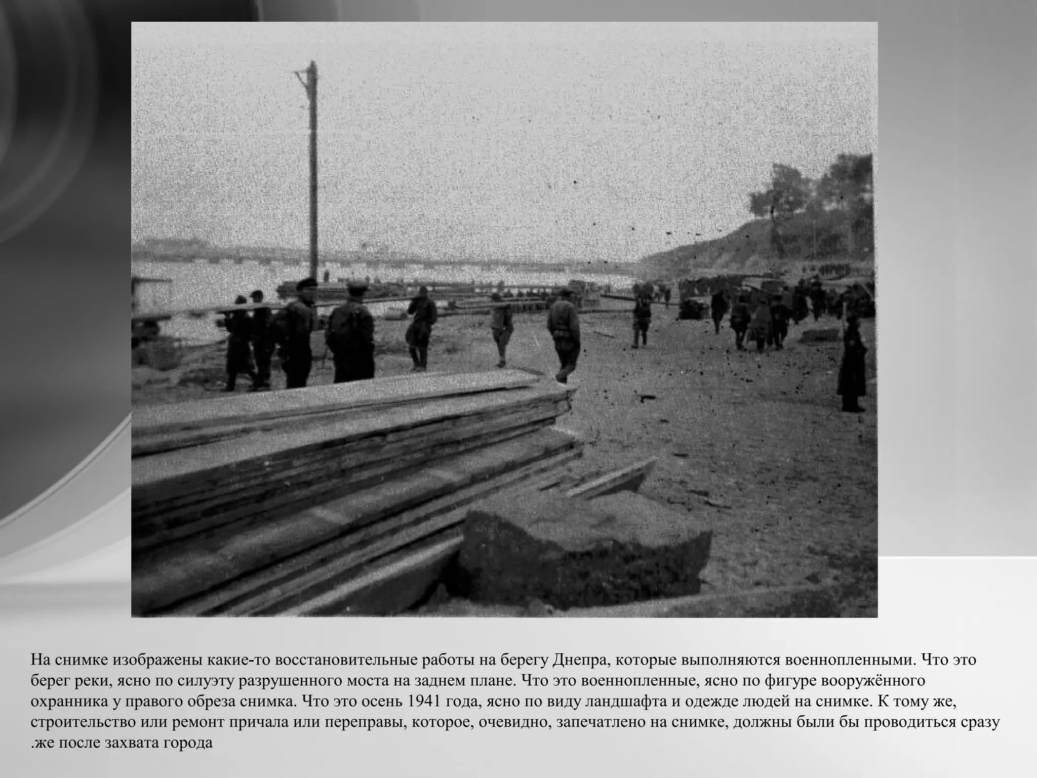На снимке изображены какие-то восстановительные работы на берегу Днепра, которые выполняются военнопленными. Что это
берег реки, ясно по силуэту разрушенного моста на заднем плане. Что это военнопленные, ясно по фигуре вооружённого
охранника у правого обреза снимка. Что это осень 1941 года, ясно по виду ландшафта и одежде людей на снимке. К тому же,
строительство или ремонт причала или переправы, которое, очевидно, запечатлено на снимке, должны были бы проводиться сразу
же после захвата города.
 