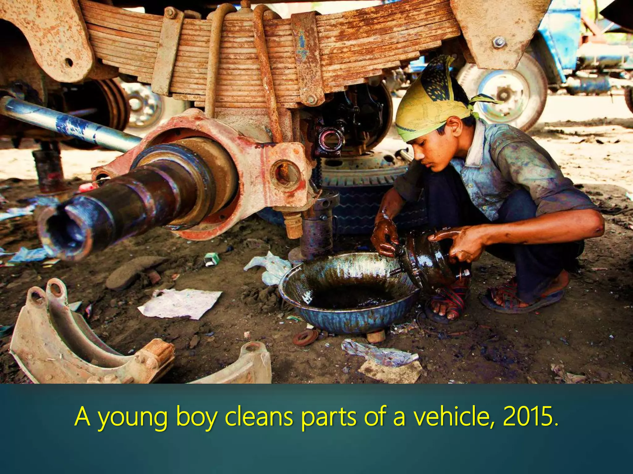 A young boy cleans parts of a vehicle, 2015.
 