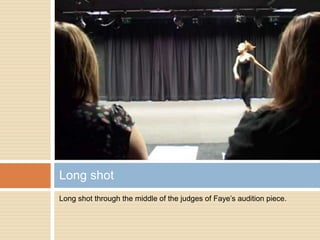 Long shot through the middle of the judges of Faye’s audition piece. Long shot