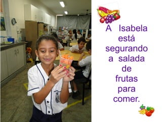 A Isabela
está
segurando
a salada
de
frutas
para
comer.
 